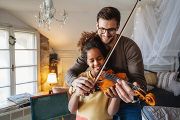 Private music man teacher giving violin lessons to African American girl at home
