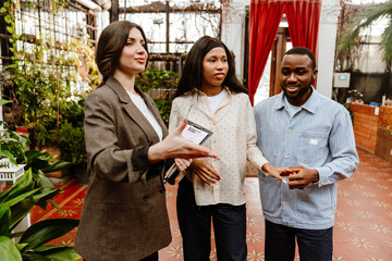 A man stands and holds the hand of a woman standing next to him while a woman standing next to them...