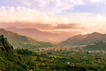 amazing sunset or sunrise in a mountain valley among slopes and hills with picturesque town on a...