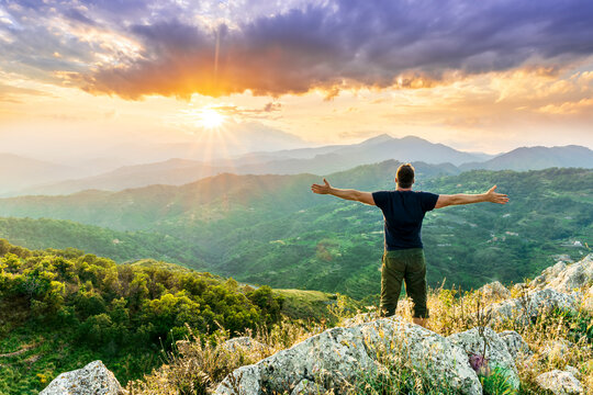 happy man watching amazing highland evening sunset, person delight with nature landscape