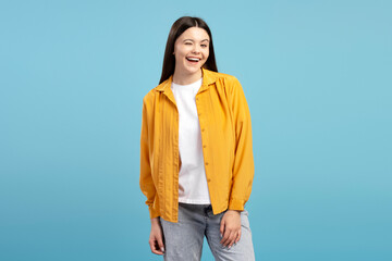 Cheerful young girl winking and smiling on blue background
