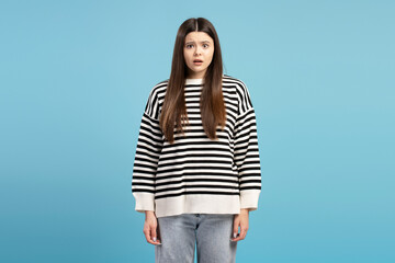 Shocked young girl expressing surprise on blue background