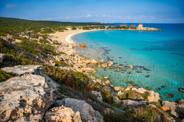 Coastline with a sandy beach and rocky shores near the northeasternmost cape of Northern Cyprus. Crystal-clear waters of a blue lagoon and the untouched beauty of the Mediterranean