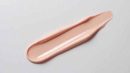 Peachy pink color correcting concealer smear isolated on a background. Thick cream texture. Closeup of skincare beauty product swipe.
