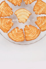 A top-down view of a glass plate filled with golden-brown palmiers, showcasing their flaky texture and spiral shape