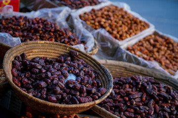 A close-up of dark and golden dates displayed in woven baskets and trays at an outdoor market, showcasing their rich texture and natural appeal.