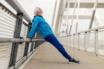 Side view of strong sporty old man doing dips on a bridge.