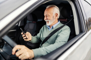 Pensioner driving a luxury car and typing on his phone.