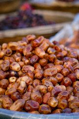 A heap of glossy, ripe dates displayed in a plastic-lined basket at a local market.