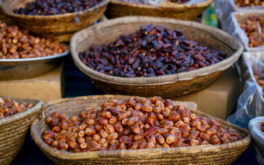 A close-up view of fresh and dried dates displayed in traditional woven baskets at a market.