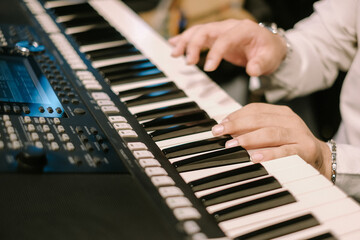 Fototapeta premium Hands playing electronic keyboard instrument close up view music scene