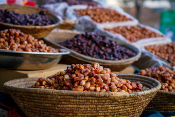 A market stall displaying fresh and dried dates in woven baskets and trays.