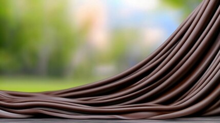 Chocolate drapes over a wooden surface, blurred natural background