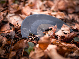 A broken vinyl record partially buried among dry autumn leaves, symbolizing abandonment, nostalgia, and the passage of time.