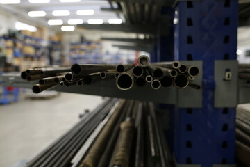 A close-up shot of metal pipes neatly arranged on a blue storage rack in an industrial warehouse setting, highlighting their metallic texture.
