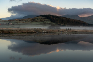 Reflections of Snowdonia mountains during golden hour in Llyn y Gadair