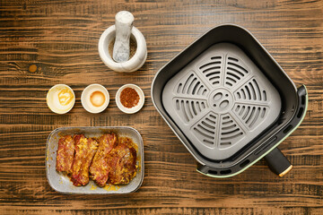 Marinated beef meat next to bowls of mustard, soy sauce, and spice blend on a wooden table