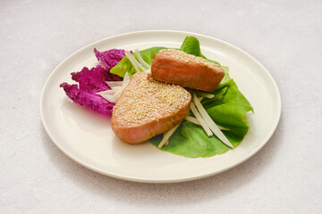 Delicious sesame-coated tuna fish served on a bed of fresh greens with vibrant vegetables