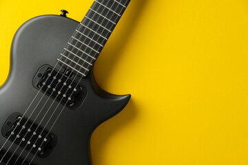 Fototapeta premium Black electric guitar on a vibrant yellow background. Flat lay, top view.