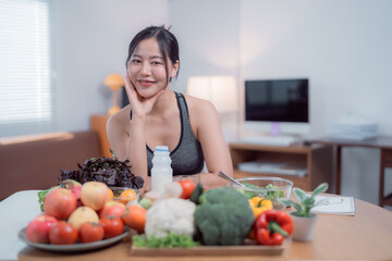 Young Asian woman sitting at a table in a bright, modern apartment, enjoying a variety of healthy foods like fruits, vegetables, yogurt, and salad