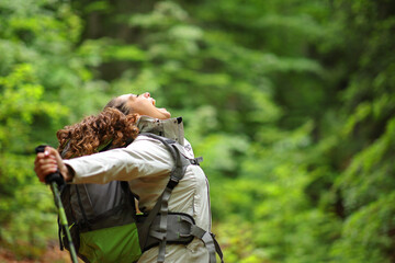 Euphoric trekker outstretching atms in a forest screaming