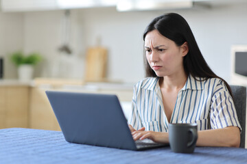 Angry asian woman checking laptop in a kitchen