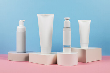 Beautiful cosmetic templates for ads, plastic cream tubes and bottles on a blue background with podiums.