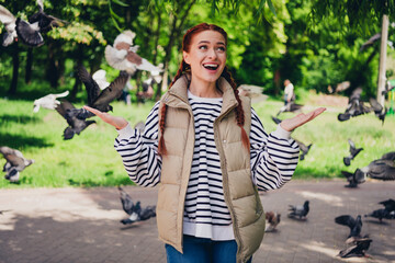 Photo of pretty young good mood girl amazed have fun pigeons flying walk outside urban city park