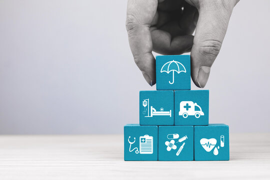 Wooden blocks with medical service icons and umbrella representing protection. Health insurance planning Concept, financial risk protection for medical expenses, and assisting in managing health risks