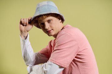 Young man showcases trendy style with playful charm against a vibrant backdrop