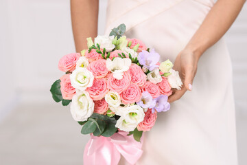 Bride with beautiful wedding bouquet on light background, closeup