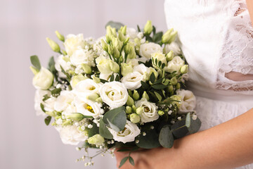 Bride with beautiful wedding bouquet on light background, closeup