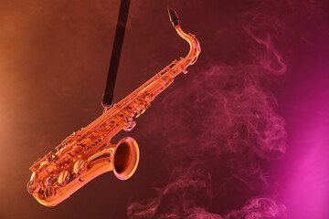 Naklejka premium Golden saxophone on color background with smoke. Space for text