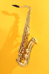 Naklejka premium Golden saxophone on yellow background. Musical instrument