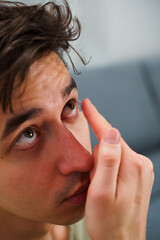 Correcting eye wellnesses with optical contact lenses. Man inserts a contact lens into eye for myopia treatment.
