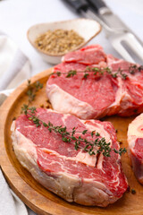 Pieces of raw beef and spices on light grey table, closeup