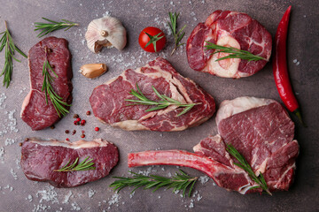Flat lay composition with pieces of raw beef, salt, rosemary and products on brown textured table