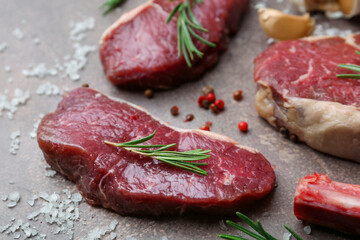 Pieces of raw beef and spices on brown textured table, closeup