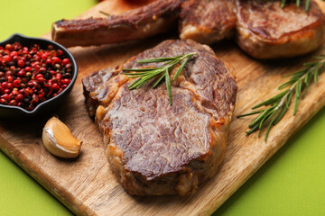 Pieces of delicious beef meat and spices on green background, closeup