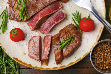 Pieces of delicious beef meat, spices and tomatoes on wooden table, flat lay