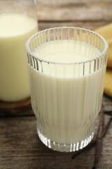 Delicious vanilla milk and pods on wooden table, closeup