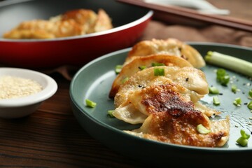 Tasty fried gyoza (dumplings) on wooden table, closeup