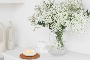 Bouquet of beautiful gypsophila flowers and eucalyptus branches in vase near decorative elements on table indoors
