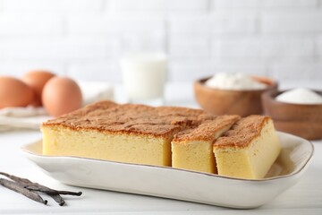 Tasty Japanese Castella sponge cake and ingredients on white table, closeup