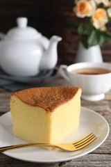 Piece of tasty Japanese Castella sponge cake and fork on wooden table, closeup
