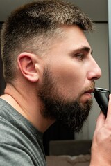 Fototapeta premium Shaping a well-groomed beard with care in an elegant bathroom while preparing for a special evening event under soft ambient lighting