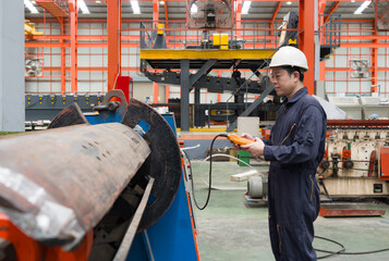 A man in a hardhat and mechanic coverall dust protection suit operates industrial equipment inside...