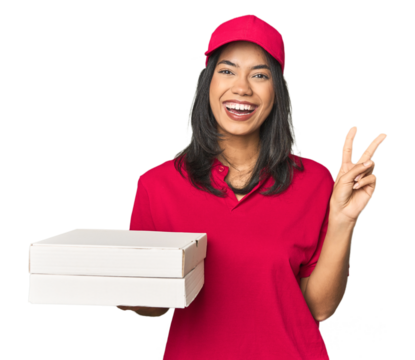 Latina delivering pizza, studio setup joyful and carefree showing a peace symbol with fingers.