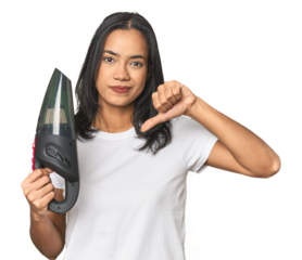 Latina with vacuum, cleaning concept showing a dislike gesture, thumbs down. Disagreement concept.