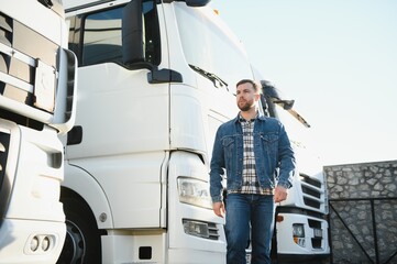 Portrait of young bearded trucker standing by his truck vehicle. Transportation service. Truck driver job